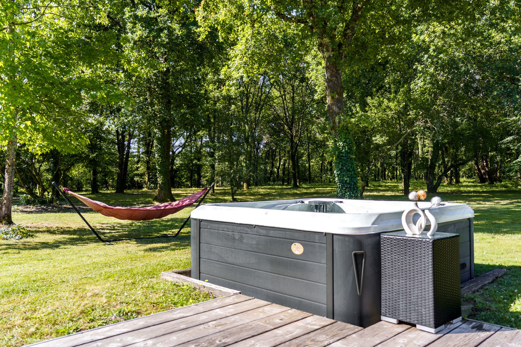 Le spa sur la terrasse en bois, le hamac tendu entre les arbres